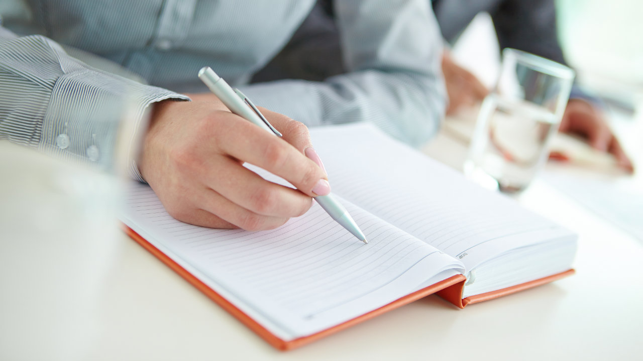 Man writing in a diary with a pen