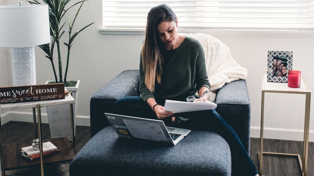 woman taking notes while working from the sofa